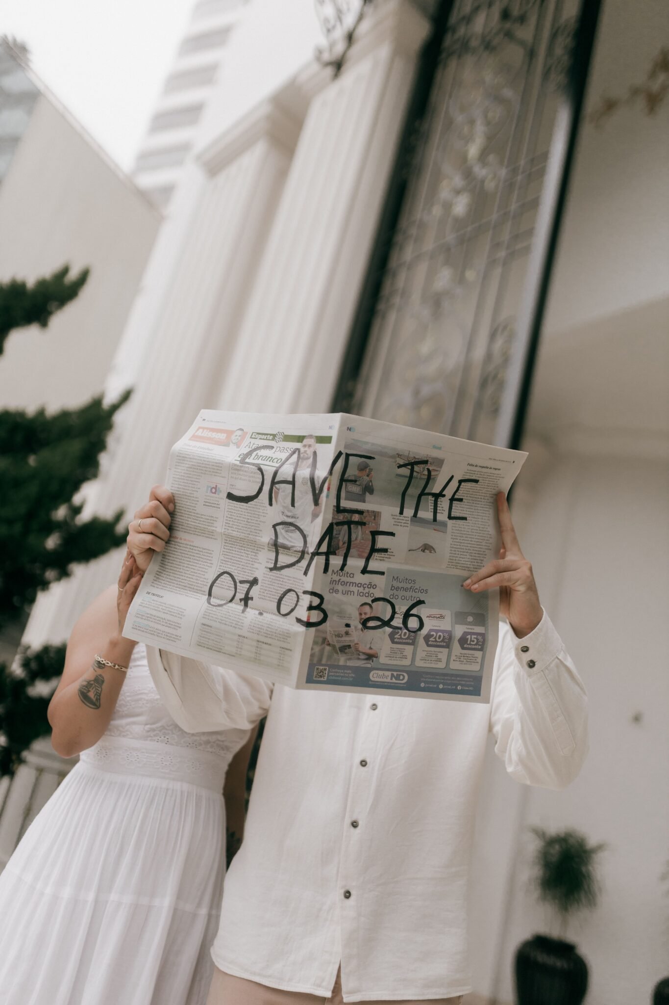 Couple holds newspaper with 'Save the Date' for a wedding announcement.